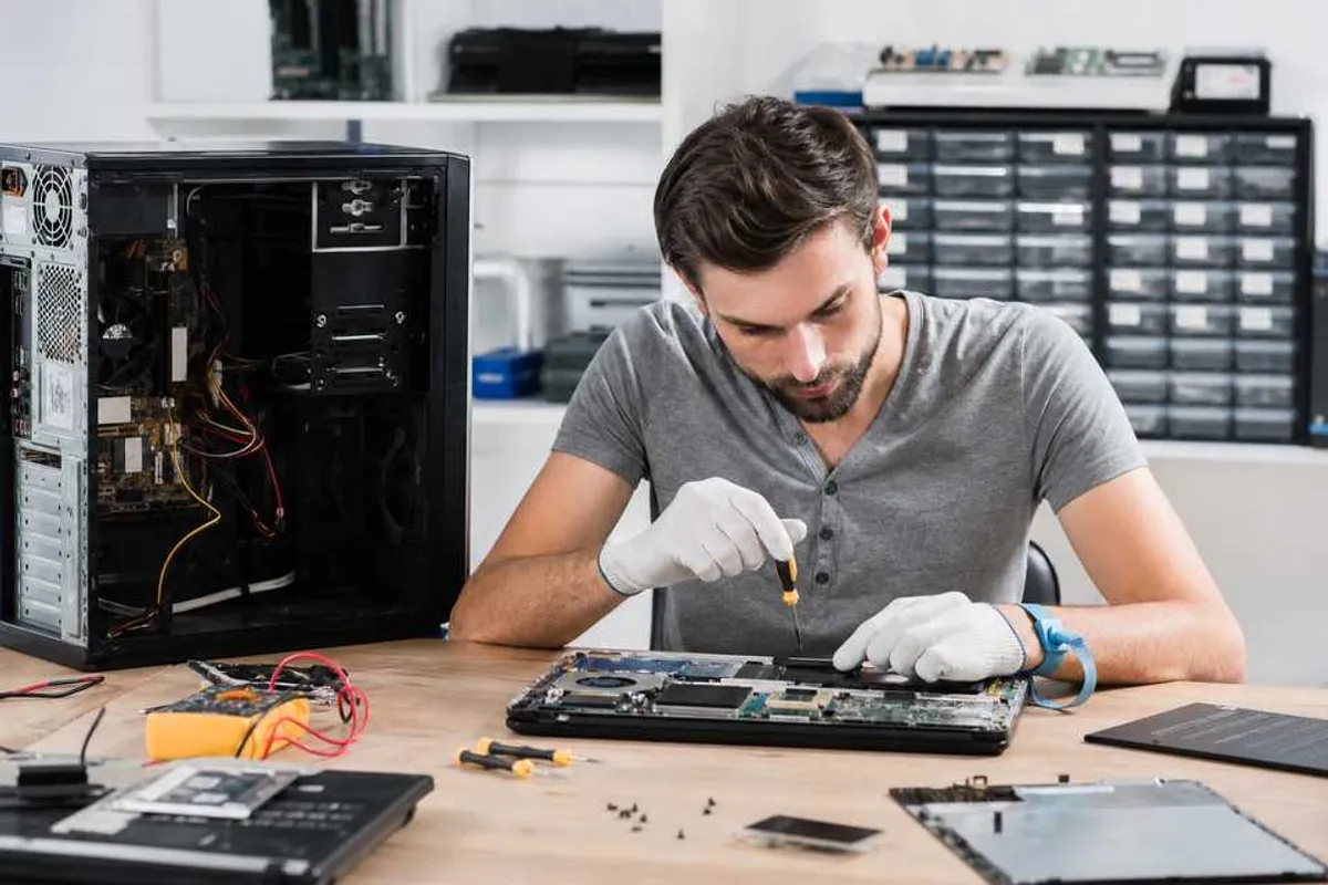 Técnico consertando computador em bancada de assistência técnica